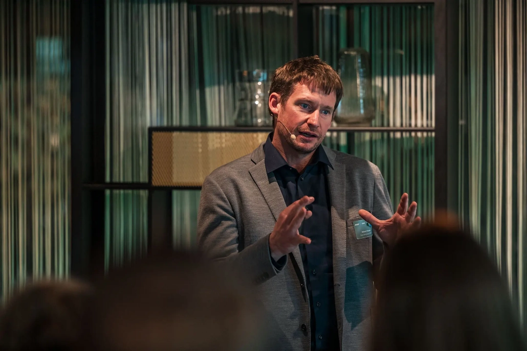 a man in a suit speaking to a group of people