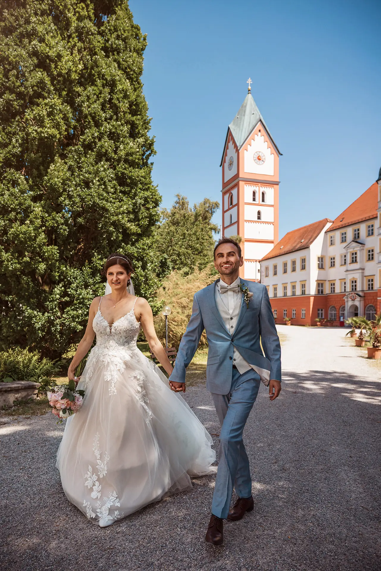 Brautpaar spaziert vor historischem Gebäude.