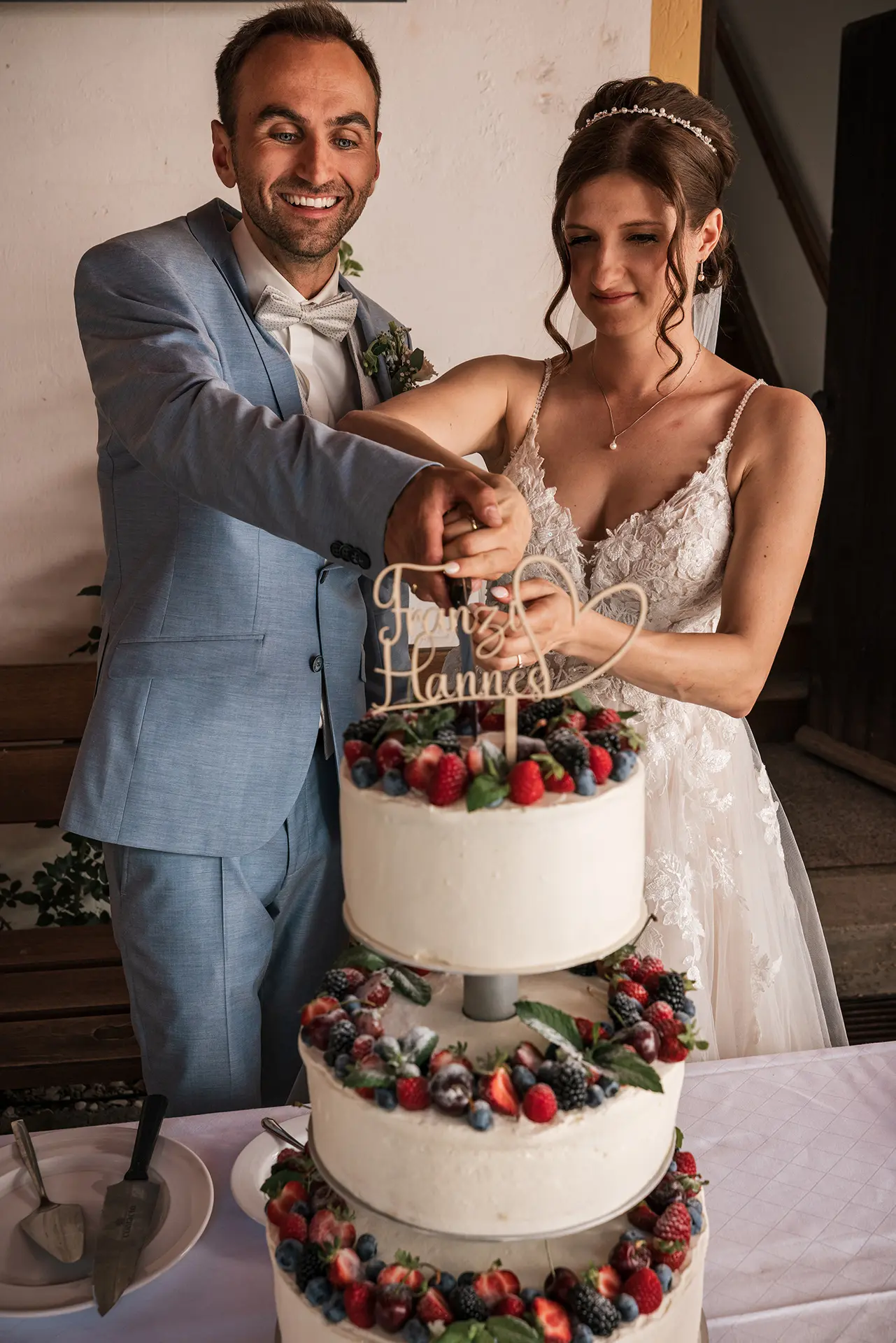 Brautpaar schneidet Hochzeitstorte zusammen.